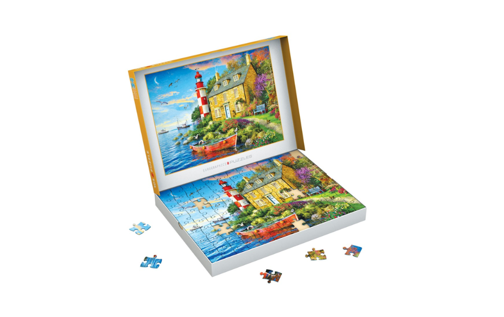 Eurographics cottage lighthouse jigsaw puzzle open box showing coastal cottage and red lighthouse with small boat pieces