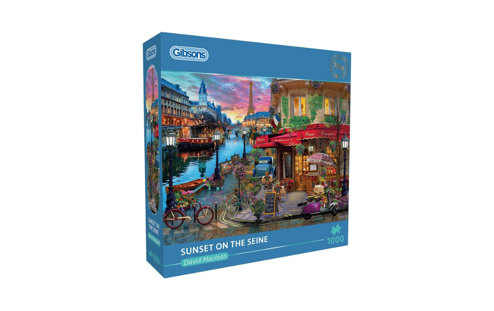 Gibsons Sunset on the Seine jigsaw puzzle box showing colourful Parisian riverside scene with cafe, bikes, boats and Eiffel Tower