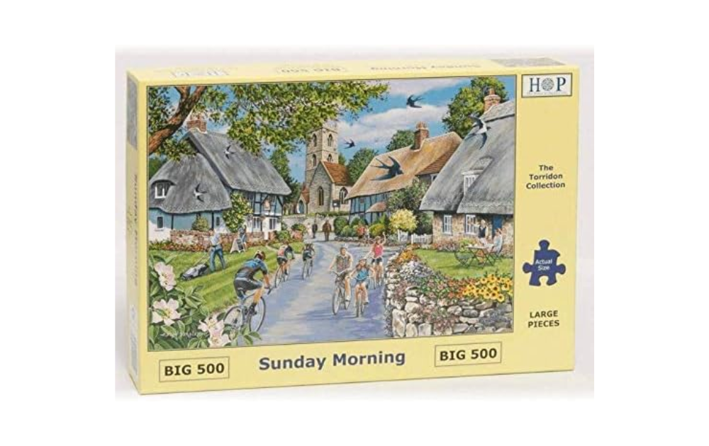 Sunday Morning 500 piece puzzle by House of Puzzles featuring a charming village scene with cyclists and cottages