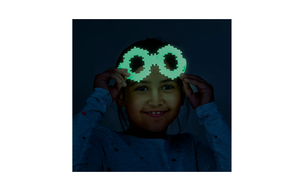 Child wearing glow-in-the-dark glasses made from Plus Plus building blocks for creative play