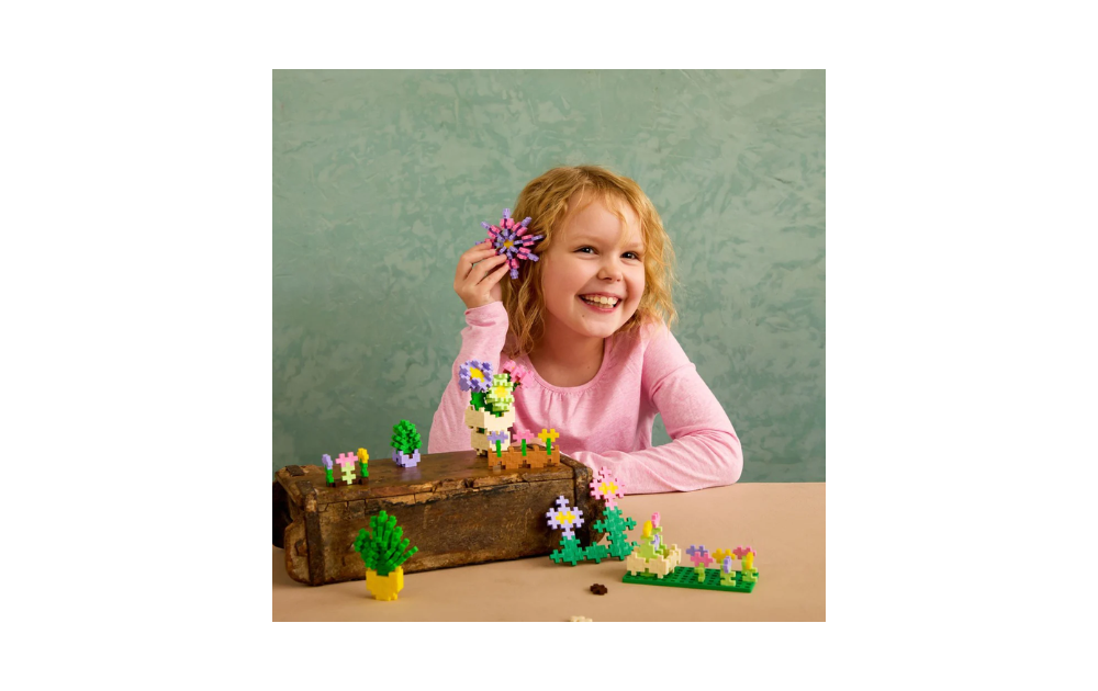 Child playing with Plus Plus flower shop building set puzzle pieces creating colorful flowers and plants
