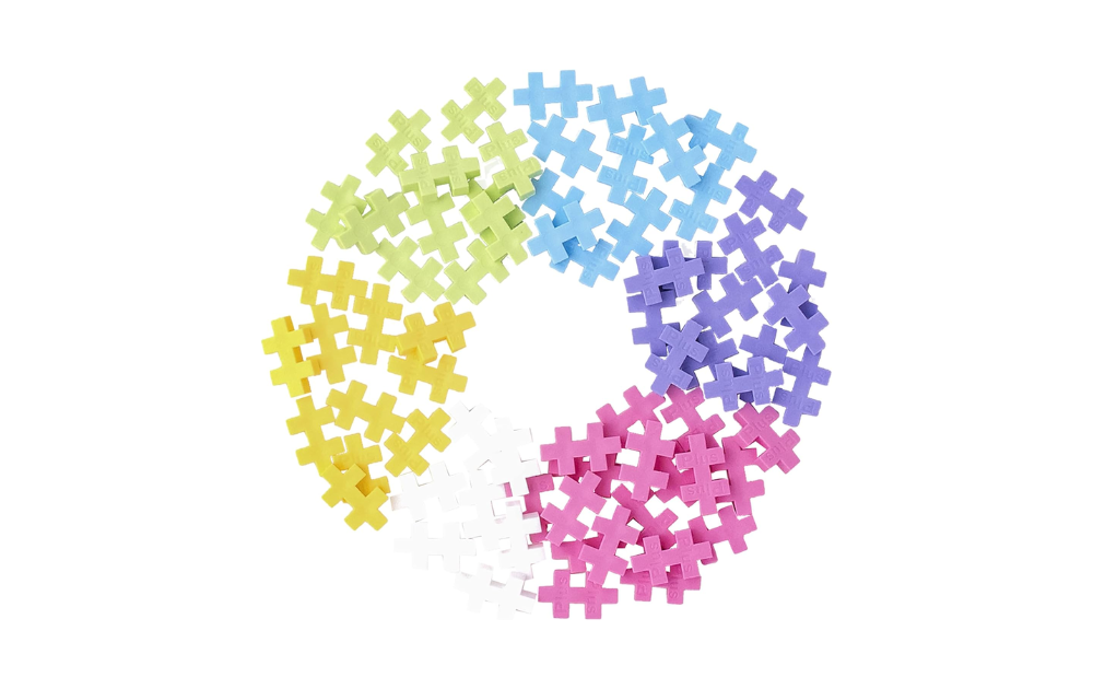 Plus Plus pastel pieces in various colors arranged in a circular pattern for creative building and fun